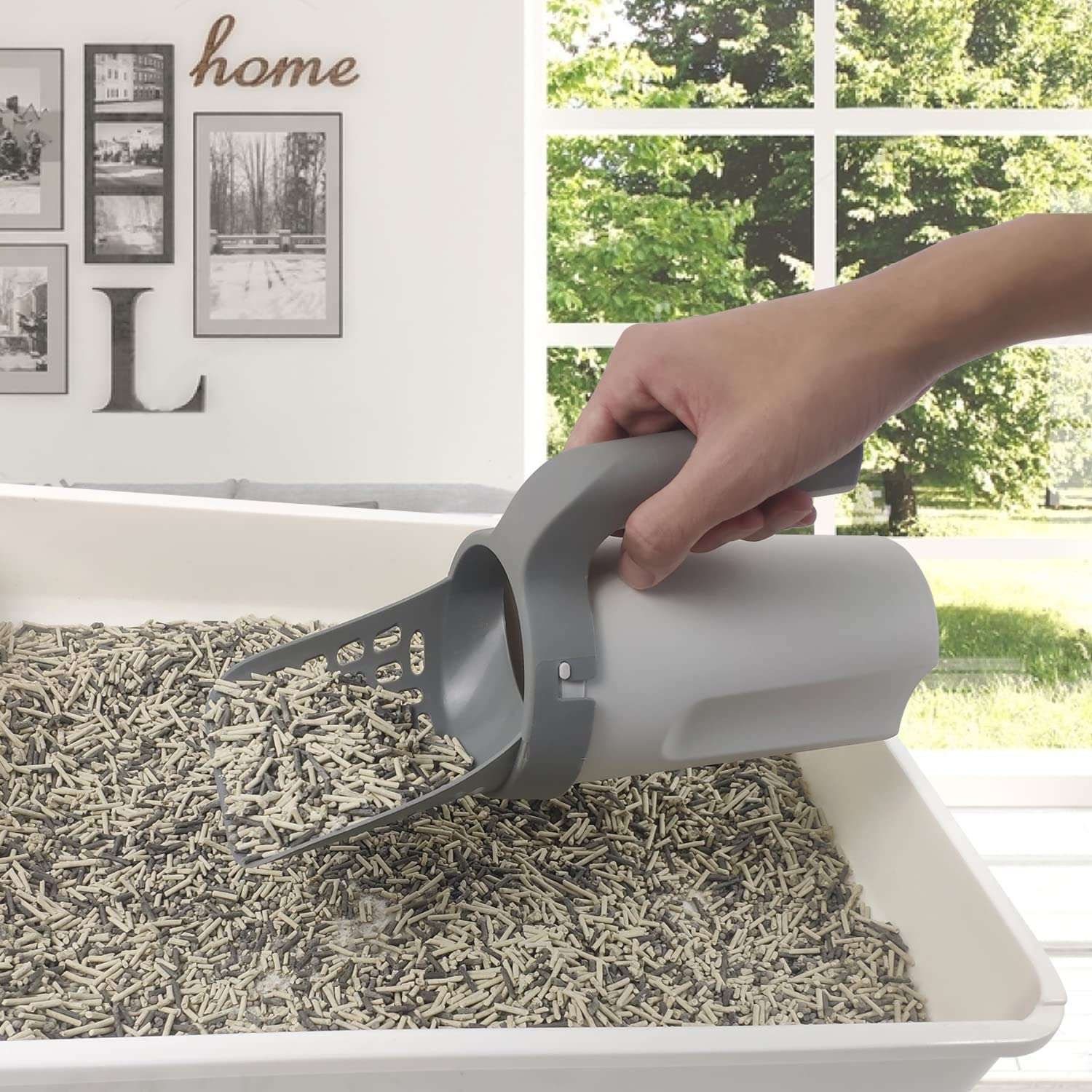 Self-cleaning cat litter shovel in use, scooping clumps from a litter box in a bright home setting.